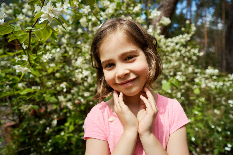 Portrait of smiling girl standing against plants in park
