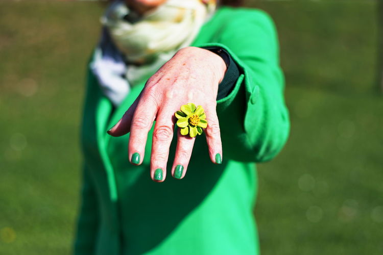 Closeup of mature's woman hand posing with green nails and green ring