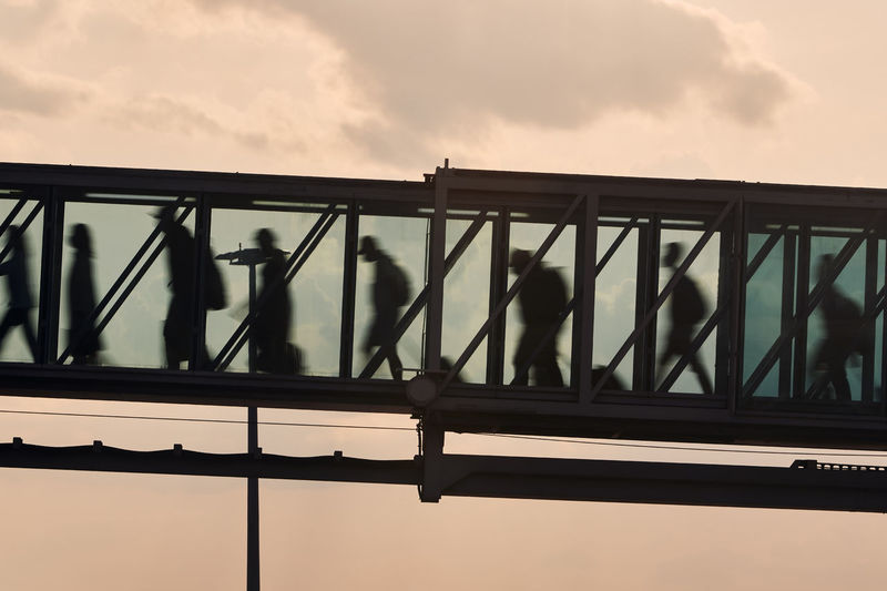 Silhouettes of people walking at busy airport. passengers walking inside boarding bridge.