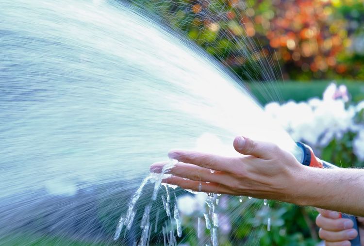 Cropped hand of person splashing water in garden