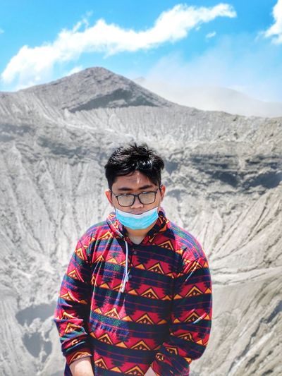 Young man wearing mask standing against rock mountain
