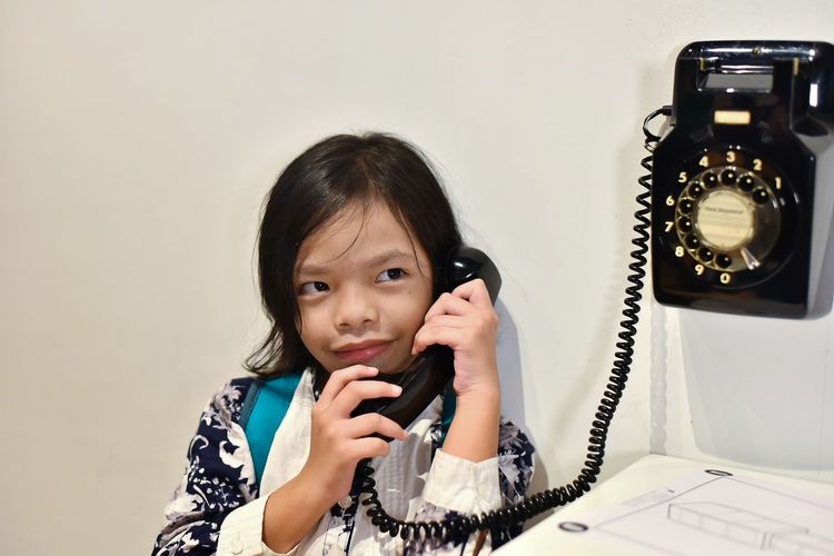 Cute girl talking on telephone in home