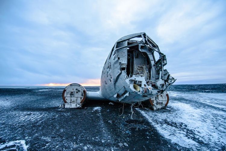 Abandoned plane on sea against sky during winter
