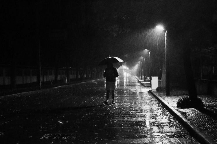 Silhouette man walking on street during rainy season