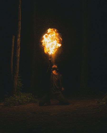 Man performing fire stunt while sitting outdoors at night