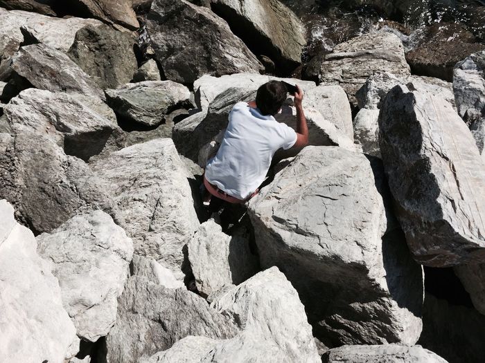 High angle view of man photographing on rocky shore