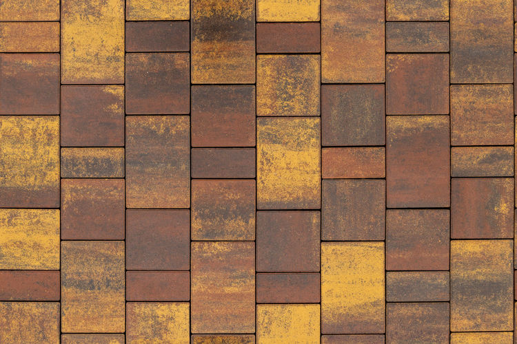 Seamless texture and background of brown and yellow melange rectangular artificial stone pavement