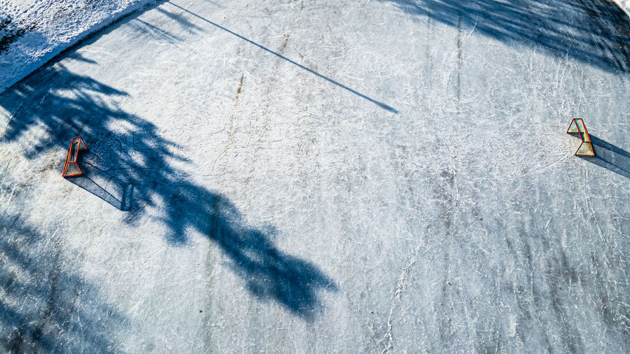 Winter outdoors ice arena with strong shadows of trees