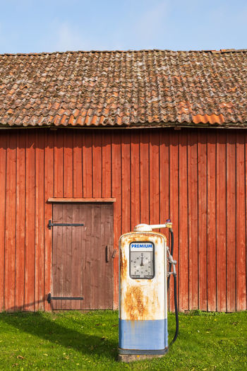 Old petrol pump by a red barn