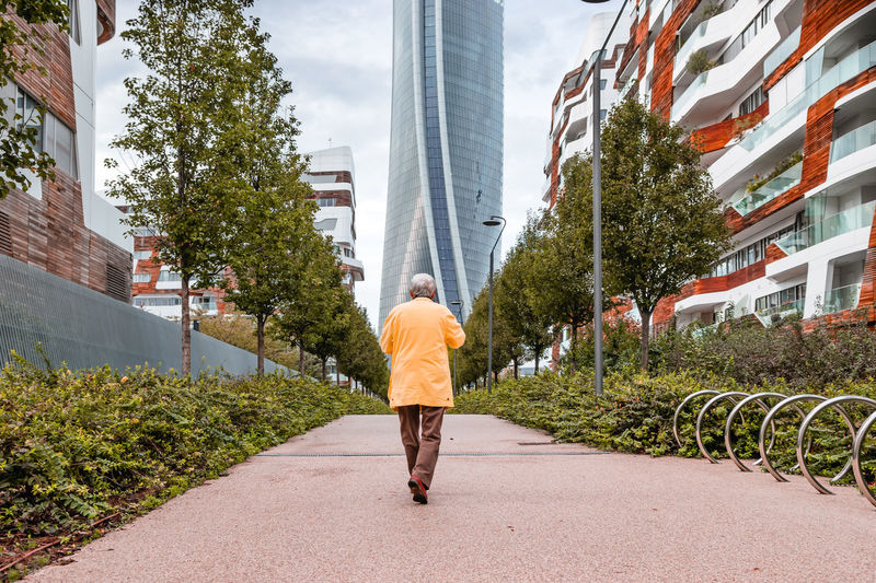 Rear view of man walking on footpath in city