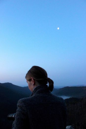 Rear view of man standing on mountain against clear sky