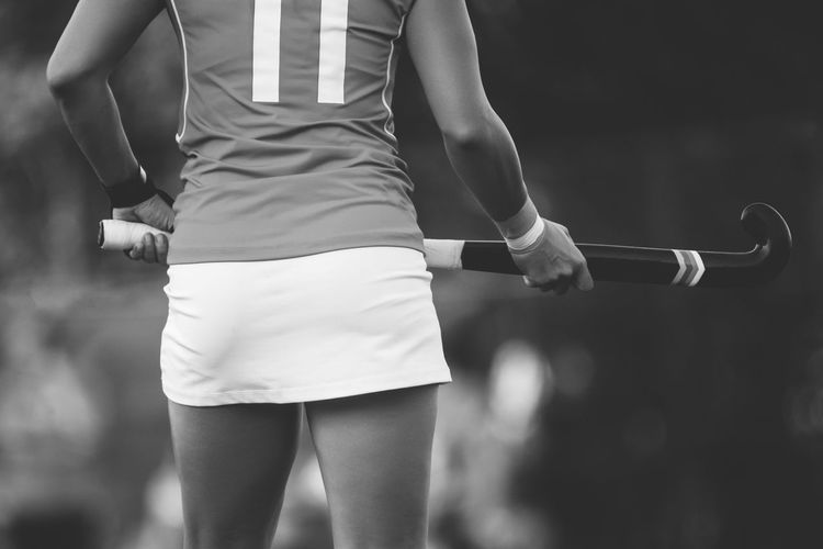 Midsection of hockey player holding bat in stadium