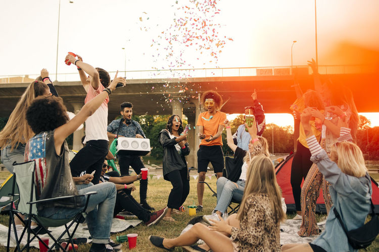 Happy friends dancing in musical event against sky in summer