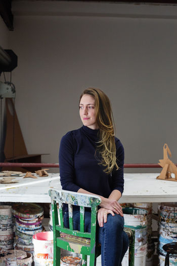 Thoughtful artist sitting on chair at table in art studio