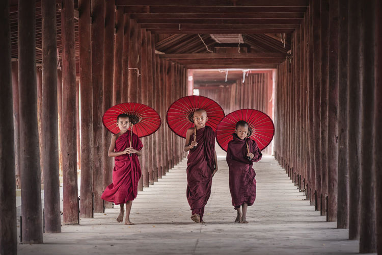 Monks with umbrellas walking in temple