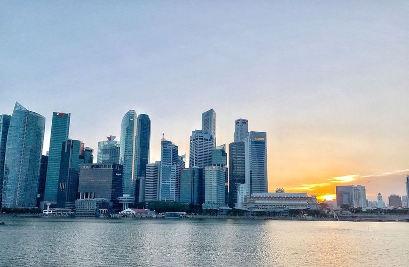 Buildings by river against sky in city