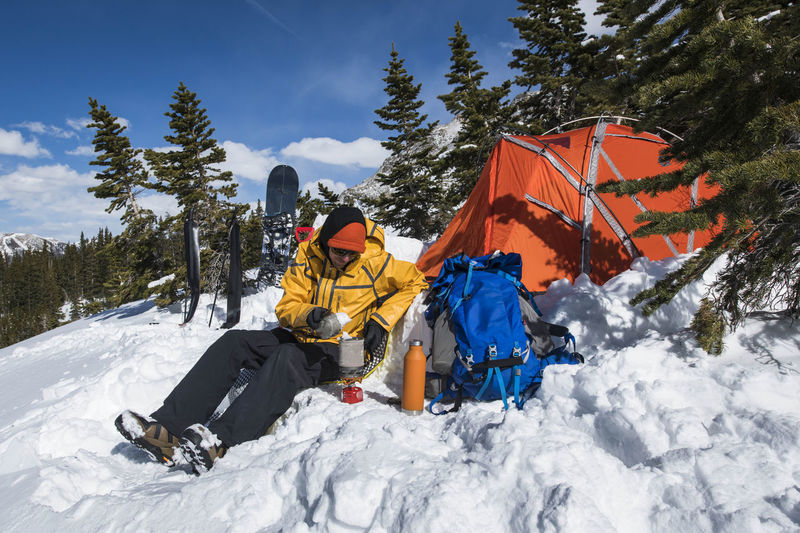 Male hiker preparing food on snow covered mountain