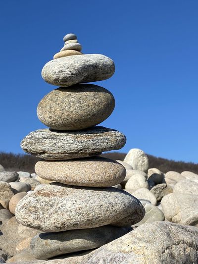 Stack of stones on rock against clear blue sky