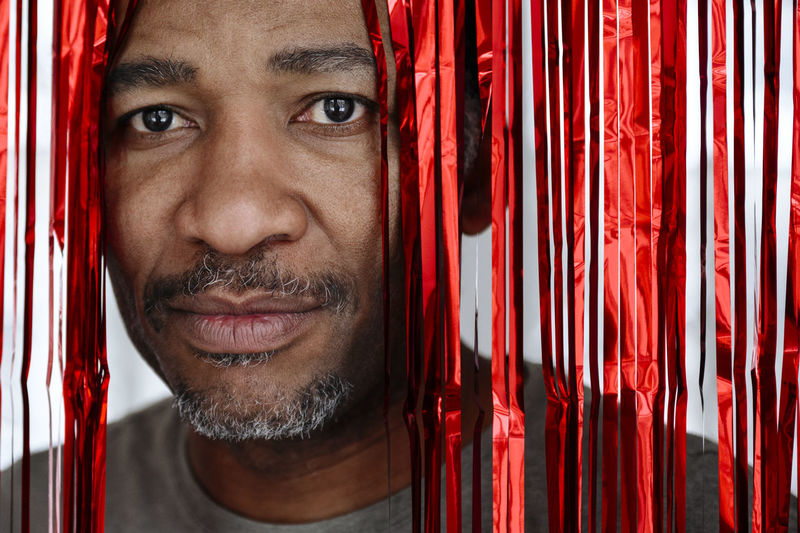 Man looking through red tinsel curtain