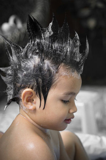 Close-up of cute shirtless boy with shampoo on hair while taking bath