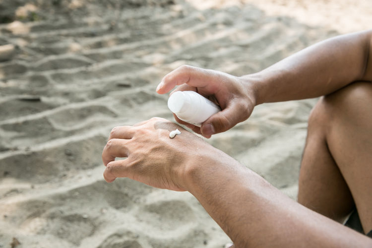 Close-up of man applying moisturizer on hand