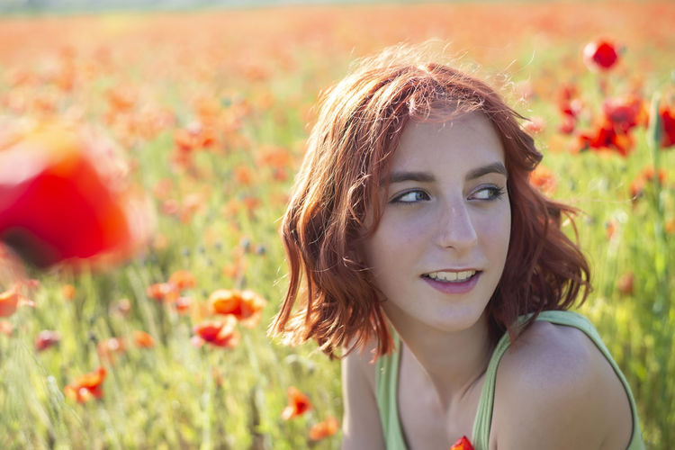 Portrait of beautiful young woman standing amidst plants on field
