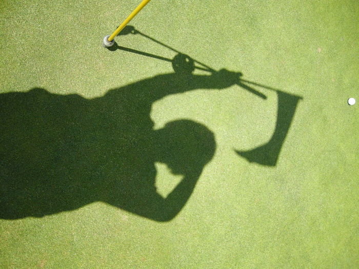 High angle view of golfer shadow on course