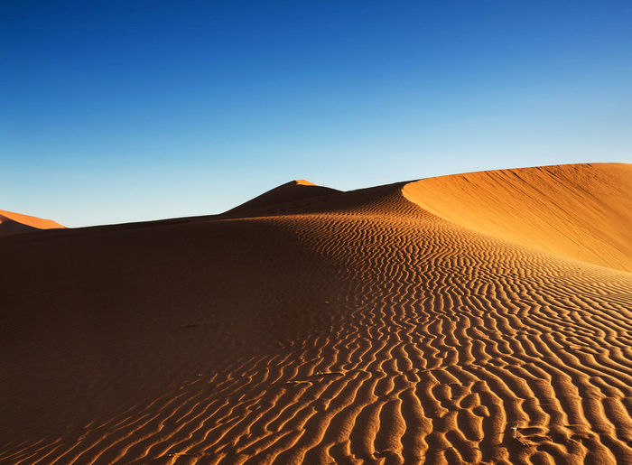 Scenic view of desert against clear blue sky