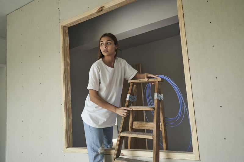 Young female architect working with wooden ladder