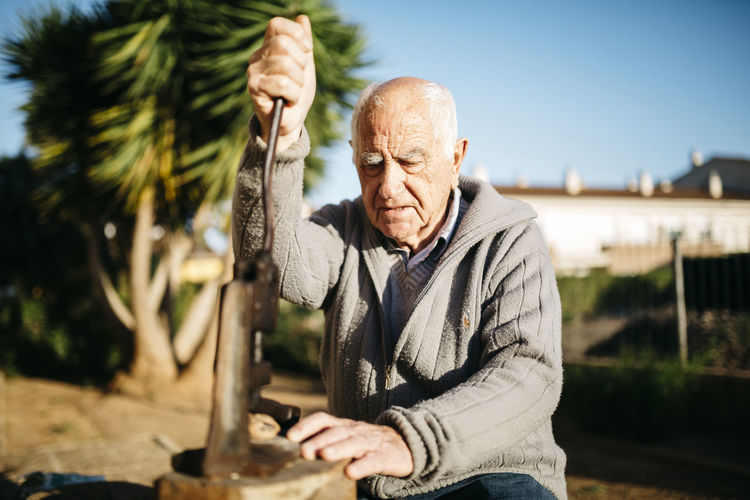 Senior man using an old tool for cracking walnuts