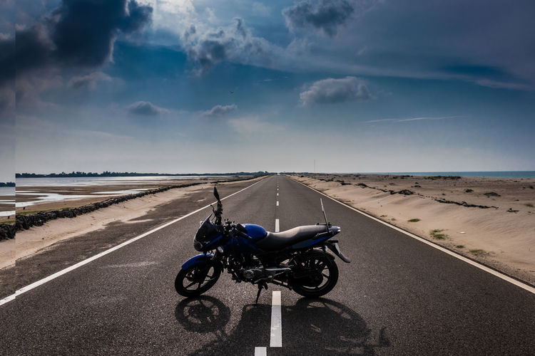 Motorcycle parked in the middle of the road with amazing sky