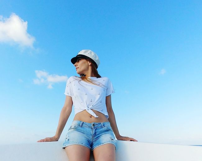 Low angle view of woman standing against sky / woman and blue sky