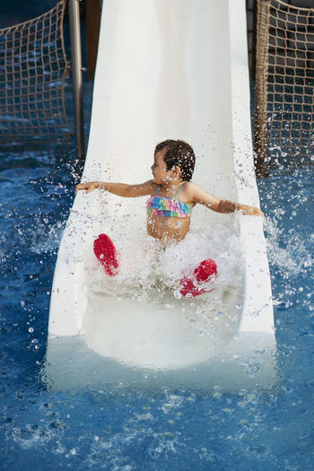Full length of girl sitting on water slide in water park
