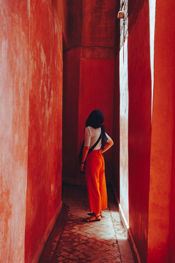 Rear view of woman standing against red wall in building