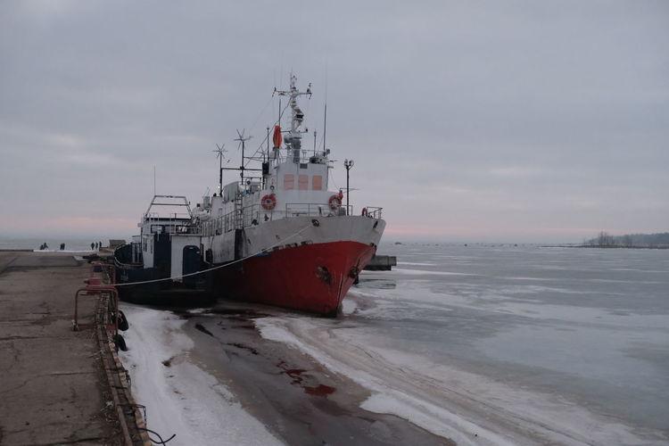 Ship moored at harbor against sky during winter