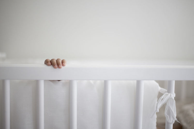 Cropped image of baby hand in crib at home