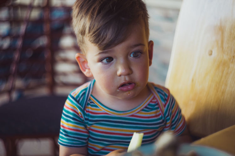 Close-up of boy eating cucumber at home