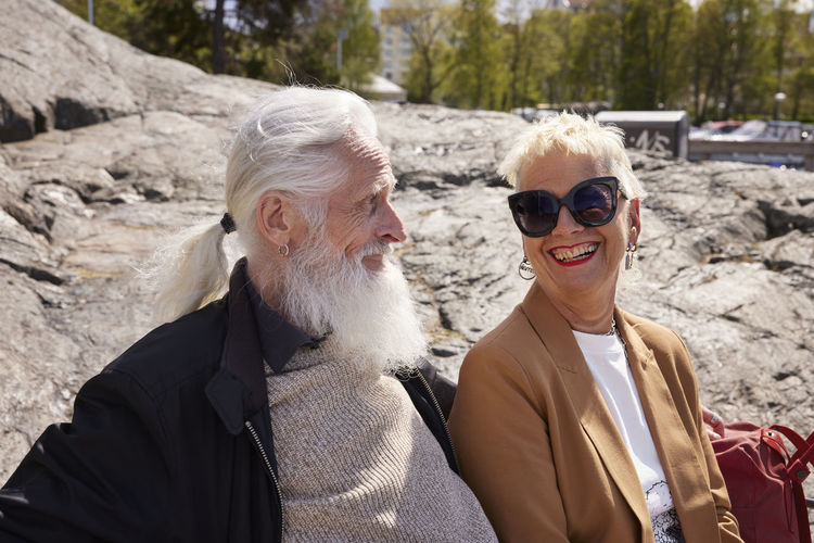 Portrait of smiling friends sitting on rock