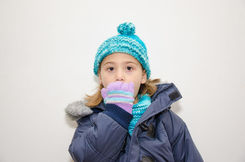 Portrait of surprised girl in warm clothes against white background