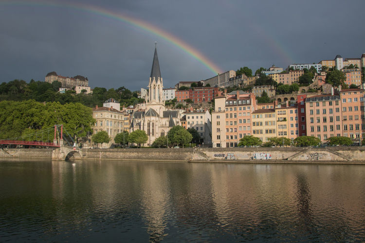 View of rainbow over river and buildings in lyon city