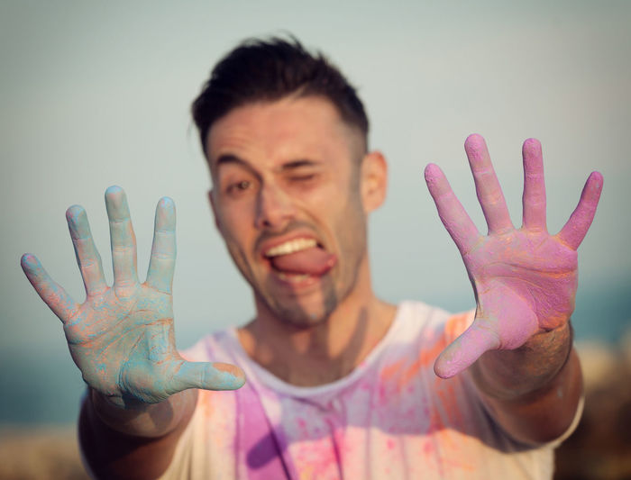 Man playing with powdered paint while standing against sky