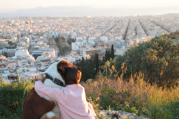 Rear view of woman with dog looking at cityscape