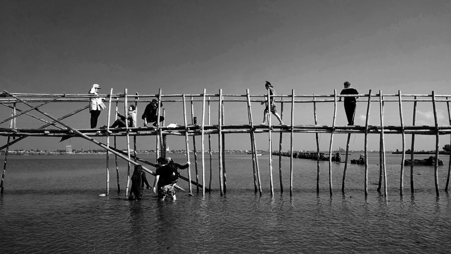 People standing on railing against sea