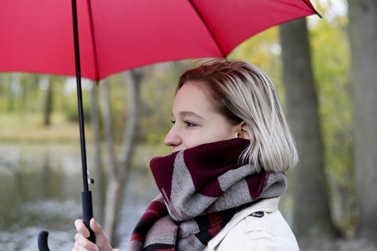 Close-up of woman holding umbrella standing by lake 
