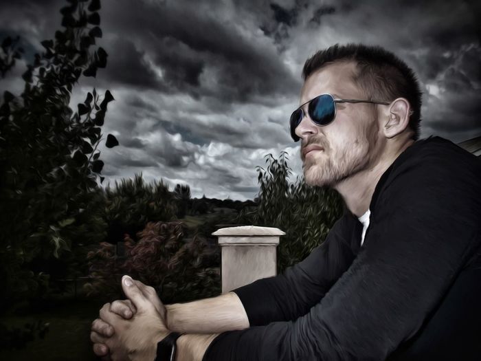 Side view of thoughtful man wearing sunglasses against cloudy sky8