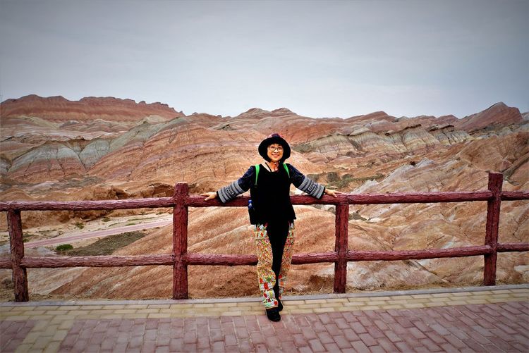 Full length portrait of woman standing against rocky mountains
