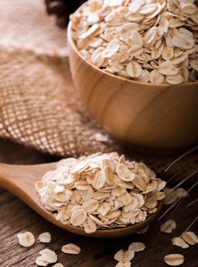 Rolled oat flakes in a wooden spoon and bowl.