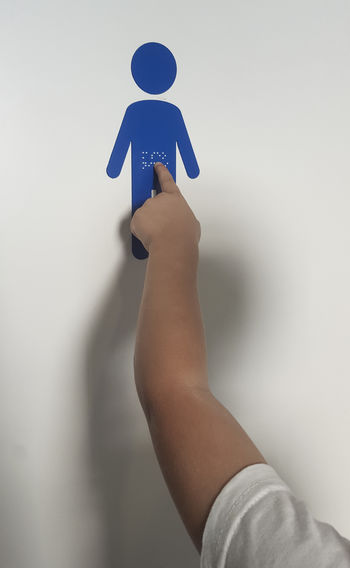 Close-up of hand holding umbrella against wall