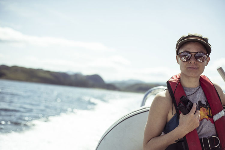 Girl on speed boat smiles in sunglasses and life vest