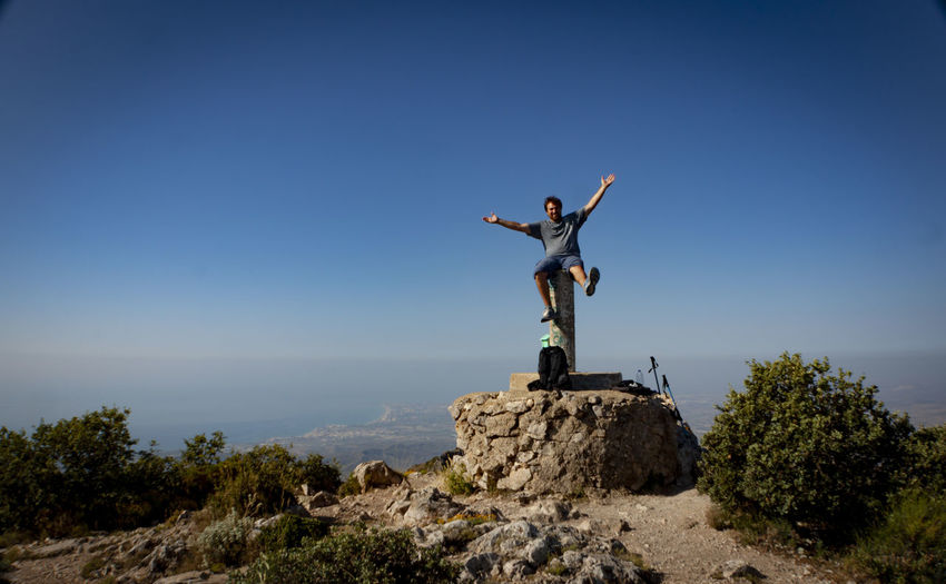 Man standing on rock against sky